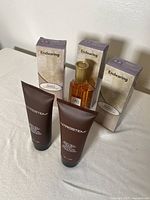 Two Introstem brown tube creams on table with three Endearing boxed perfumes behind them.