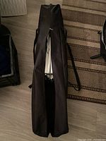 Closed black carrying bag with visible folded metal frame inside