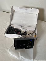 Open box showing the LCD monitor and wired rear view camera inside the box with protective packaging.