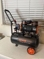 Front and side view of the black and orange Vevor air compressor showing branding and handle.