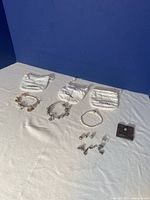 Three Pandora bracelets displayed with multiple charms and three white Pandora branded pouches on white cloth background.
