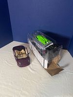 Photo showing the purple convertible Maisto Lamborghini model and the green RC boat with controller in packaging on table with blue background.