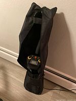Metal detector standing inside a black carrying bag, partially zipped open to show control panel.
