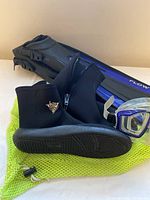 Photo showing black neoprene deep sea booties size 11 with zipper, blue and black adjustable fins labeled 'FLOW', and a partial view of the mask and snorkel lying on a bright green mesh bag.