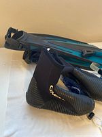 Photo showing ONeill black neoprene booties with rubber soles and Velcro straps next to Body Glove fins.