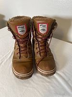 Front view of brown leather Pajar Canada snow boots with laces and fur lining.