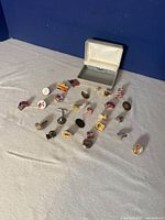 Top view of various vintage pins and small display box arranged on a flat surface with blue background.