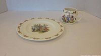 Overall view of Royal Doulton Bunnykins cup and side plate showing porcelain items with colorful bunny and floral illustrations.