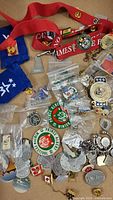 Various collector pins spread out including red lanyard, Prince Albert Winter Festival pins, and event pins