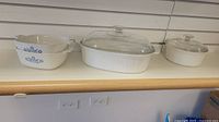 Two CorningWare casserole dishes displayed side by side on wooden surface