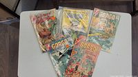 Lot of approximately 8 Gorgo comics displayed on table, packaging material partially visible, colorful monster-themed cover art shown
