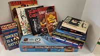 Photo showing a stack of about 14 hockey books and the boxed Hockey Night in Canada VCR game.