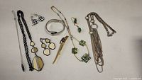 Photo of assorted jewelry including fused glass necklace and earrings, silver-tone and gold-tone pieces, and multiple necklace and earring sets