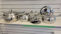 Full set of five pots and pans with lids arranged on shelf