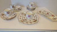 Photo of Royal Albert Petit Point china including cups, small plates, saucers, cream and sugar, and serving plates displayed on a table.