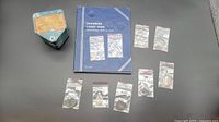 Lot contents including small plastic bags of vintage Canadian coins, blue coin collection album, and small metal coin bank.