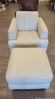 Front view of white leather chair with ottoman placed in front.