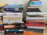 Photo of assorted books stacked in two piles showing titles and authors.