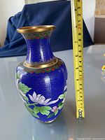 Photo showing the vase next to a tape measure indicating height of about 7.5 inches, showcasing the blue color with floral patterns and gold rim.