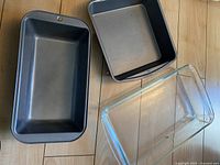 Three rectangular baking pans: two metal and one glass.