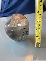 Photo showing the small round pottery container with a lid, measuring about 4 inches in height, with textured and crackled glaze on lid and darker finish on body.