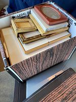 Box filled with assorted picture frames stacked inside, showing variety in size and frame style.