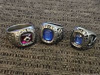 Three vintage American Bowling rings placed on fabric showing inscriptions and center stones.