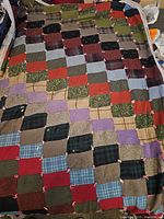 Full view of the antique patchwork quilt showing multiple fabric squares in various colors and patterns.