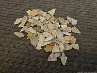 Photo showing a large pile of various stone arrowheads in multiple shapes and natural stone colors such as beige, brown, and gray.