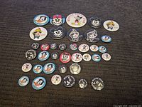 Overview of the full assortment of Disney character pins arranged on fabric showing front faces and designs.