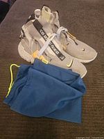 Side angle view showing the sneakers and blue drawstring bag.