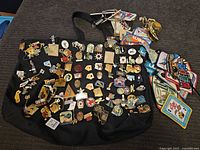 Overview shot of a black bag covered and surrounded by numerous bowling pins, patches, and memorabilia.