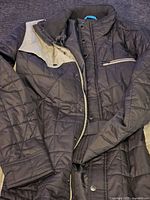 Black Hurley quilted jacket laid flat showing front view with zipper and snap button closure, ribbed collar, and zippered chest pocket.