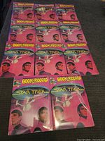 Seventeen sealed Star Trek Book & Record sets displayed flat on a black surface, front covers visible featuring Star Trek characters and ship.