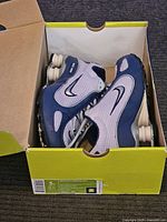 Nike Shox Monster sneakers in original box, showing left and right shoes side by side with visible Nike Swoosh logos and Shox cushioning columns in heel area.