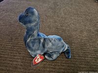 Blue Bronty Beanie Baby plush toy shown on brown carpet, clear view of the entire body and head profile.