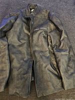 Full view of the black leather Mac Tools jacket showing front zipper and full length sleeves.