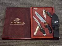 Display of the three knives and black fabric sheath inside the presentation case.