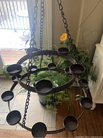 Full view of 2-tier metal hanging candle candelabra suspended by chains indoors.