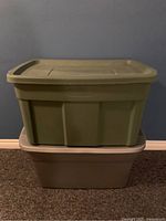 Stacked photo of two large plastic storage containers, green Rubbermaid tote on top of grey Sterilite tote with light grey lid.
