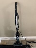 Full view of the Bissell upright stick vacuum standing upright with power cord wrapped on handle.