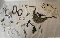 Full overview of assorted costume jewellery pieces laid out on a white cloth including necklaces, bracelets, rings, and earrings.