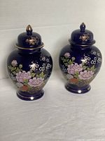 Pair of cobalt blue Kutani ginger jars with floral hand-painted decoration and lids on neutral background.