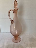 Front view of pink Depression glass decanter showing handle, body, and stopper.