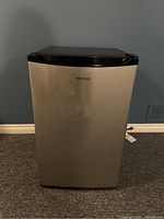 Front view of the Whirlpool mini fridge showing stainless steel finish and black top.