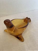 Amber glass seal figurine shown from front angle highlighting smooth rounded head and front flippers.