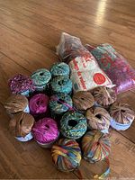 Overall shot showing 17 balls of wool yarn in various colors and two bags of wool filler.