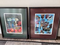 Two framed boat art prints side by side: left with green mat, right with burgundy mat showing boats