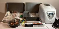Full lot contents including bread maker and bakeware on table
