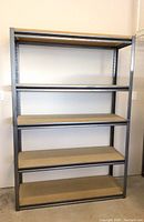 Front view of shelving unit against a light-colored wall showing four wooden shelves supported by a galvanized metal frame.